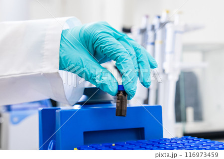 A chemist uses a vortex mixer to shake samples before HPLC analysis 116973459