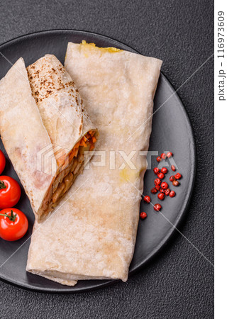 Delicious juicy roll or shawarma with chicken, tomatoes, salad and sauce 116973609