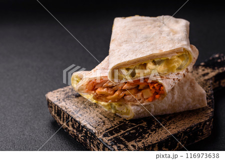 Delicious juicy roll or shawarma with chicken, tomatoes, salad and sauce Delicious juicy roll or shawarma with chicken, tomatoes, salad and sauce 116973638