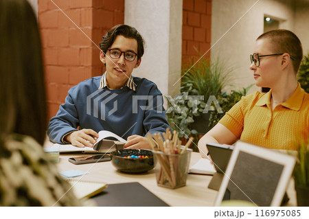 Young biracial man wearing eyeglasses telling about survey results during meeting with marketing team in modern office Young biracial man wearing eyeglasses telling about survey results during meeting with marketing team in modern office 116975085