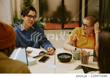 High angle view of diverse young men and women working in team on new business strategy during meeting in office 116975086