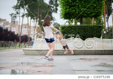 Young mother circling her daughter in her arms outside 116975286