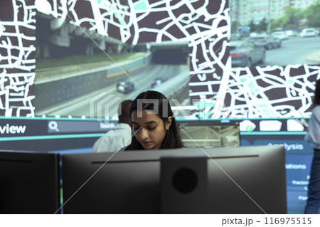 Indian woman locating delivery trucks in traffic via satellite map with gps coordinates, monitoring route and destination to ensure order shipment. Agency employee uses public surveillance system. Indian woman locating delivery trucks in traffic via satellite map with gps coordinates, monitoring route and destination to ensure order shipment. Agency employee uses public surveillance system. 116975515