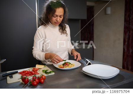 Woman preparing a pasta dish in a modern kitchen with fresh ingredients 116975704