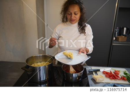 Woman preparing a pasta meal in modern kitchen with fresh ingredients 116975714