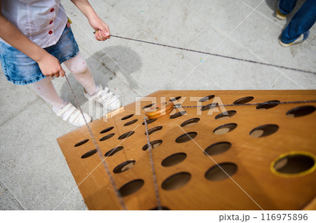 Child playing a wooden puzzle game outdoors on a sunny day 116975896