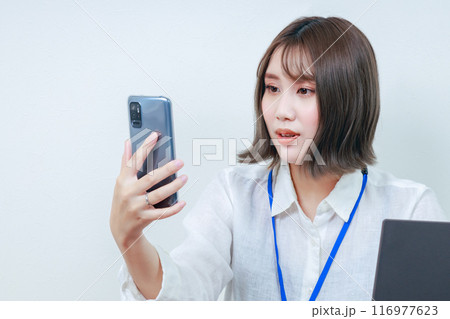 スマホを見て驚きの表情を見せる若い女性 116977623