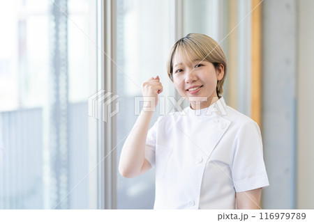 ケーシー白衣を着る金髪ショートヘアの若い女性整体師（髪色自由、自分らしく働く、職場環境） 116979789