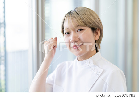 ケーシー白衣を着る金髪ショートヘアの若い女性整体師（髪色自由、自分らしく働く、職場環境） 116979793