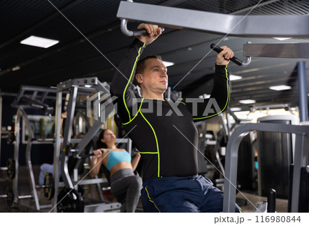Man exercising back on pull down lever machine in gym Man exercising back on pull down lever machine in gym 116980844