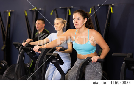 Group of people performs aerobic training workout cardio routine on spin bike 116980888