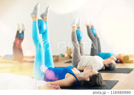 Woman exercising with bender ball during group training at gym. Woman exercising with bender ball during group training at gym. 116980990