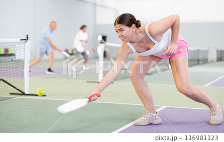 Expressive young girl playing pickleball in indoor court 116981123