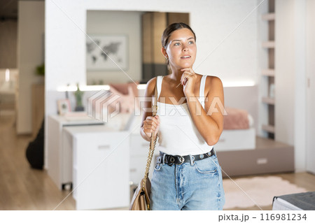 Young girl watching large stock of goods in furniture shop Young girl watching large stock of goods in furniture shop 116981234