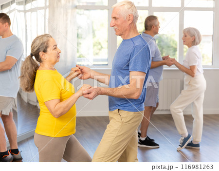 Senior man dancing bachata with female partner during group class 116981263