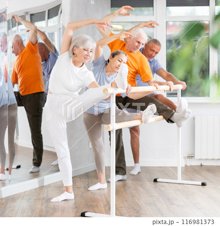 Ballet pose grand batman - elderly women and men at choreography lesson Ballet pose grand batman - elderly women and men at choreography lesson 116981373