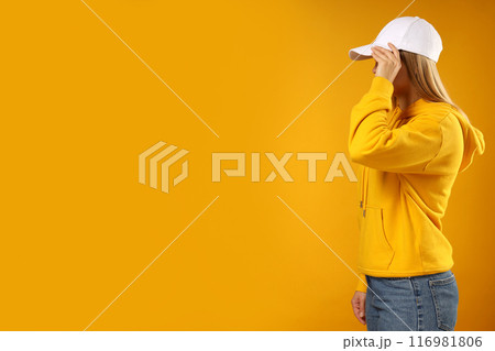 A young woman in a yellow hooded sweatshirt and cap 116981806