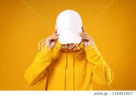 A young woman in a yellow hooded sweatshirt and cap 116981807