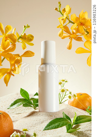 Close up shot photography in natural concept with flower, fruit and plant. An unbranded cosmetic bottle displayed on the sand, some green plants, oranges and yellow orchid on both sides 116983226