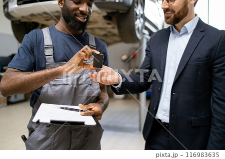Mechanic handing car keys to businessman in auto repair shop 116983635