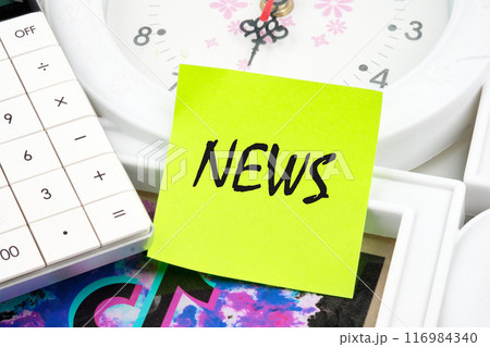 News word written on a light green sticker on the background of a clock near the calculator 116984340