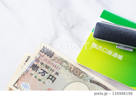テーブルの上に置かれた銀行の預金通帳と印鑑、1万円札 テーブルの上に置かれた銀行の預金通帳と印鑑、1万円札 116986198