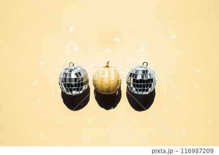 One tiny pumpkin and some disco balls on a row. 116987209