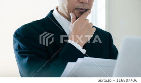 書類を見て悩むビジネスマン 116987436