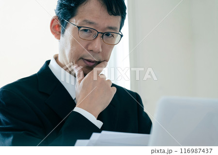 書類を見て悩むビジネスマン 書類を見て悩むビジネスマン 116987437