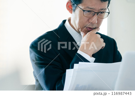 書類を見て悩むビジネスマン 116987443