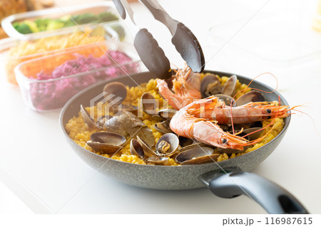 トングを使ってパエリアにエビを盛り付ける 116987615
