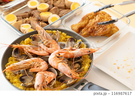 トングを使ってパエリアにエビを盛り付ける 116987617