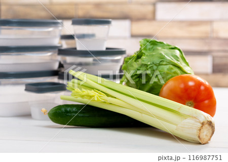 A stack of plastic containers and raw vegetables on the table. Storage for vegetables and fruits in plastic containers 116987751