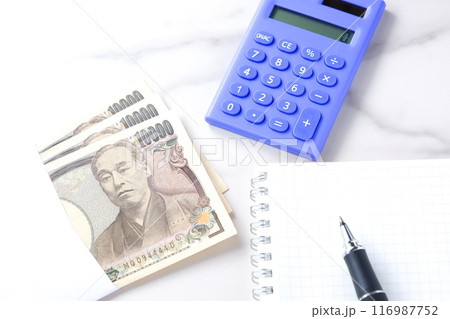 福沢諭吉の肖像の一万円紙幣と電卓、メモ帳とペン 116987752