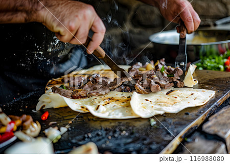 Turkish kebab dish, the cook forms a dish of pieces of meat fried on a spit, served on thick pita bread with the addition of herbs and vegetables and sauces Turkish kebab dish, the cook forms a dish of pieces of meat fried on a spit, served on thick pita bread with the addition of herbs and vegetables and sauces 116988080