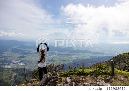 伊吹山に登って両手で伸びをして景色を眺めている帽子をかぶった若い女性 116988611
