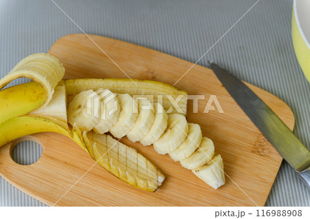 Peeled and sliced banana on a cutting board. 116988908