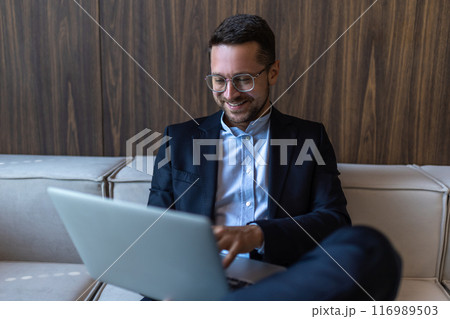 Confident businessman in glasses working on laptop computer in office interior Confident businessman in glasses working on laptop computer in office interior 116989503