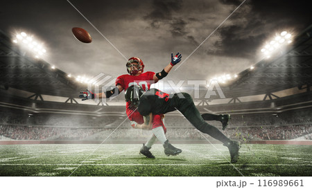 Dynamic image of two American football players in motion on open air arena with filled stands, competing for victory. 3D render of stadium 116989661