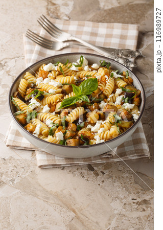 Fusilli pasta with fried eggplant, garlic and feta cheese close-up in a bowl. Vertical Fusilli pasta with fried eggplant, garlic and feta cheese close-up in a bowl. Vertical 116989727