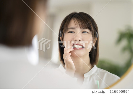 歯磨き中に歯茎をチェックするアラサーの女性 歯磨き中に歯茎をチェックするアラサーの女性 116990994