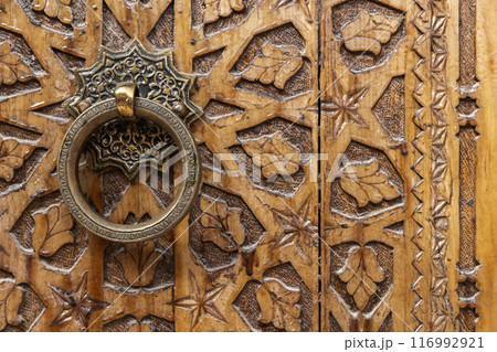Ancient round copper handle of an old wooden door Ancient round copper handle of an old wooden door 116992921