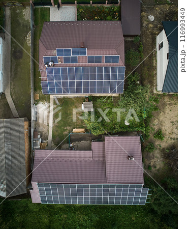 Men technicians mounting photovoltaic solar moduls on roof of house. Workmen in helmets installing solar panel system outdoors. Concept of alternative and renewable energy. Aerial view. Men technicians mounting photovoltaic solar moduls on roof of house. Workmen in helmets installing solar panel system outdoors. Concept of alternative and renewable energy. Aerial view. 116993449