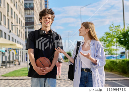Guy and girl, college students walking together along street of city 116994718