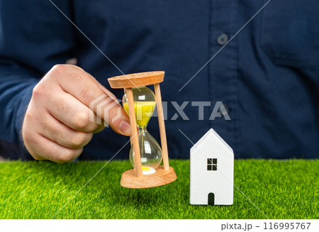 A man holds an hourglass near his house. Rent and realty. Mortgage and loan payments. Limited supply. Long-term lease terms. Legislation on evicting tenants or squatters. A man holds an hourglass near his house. Rent and realty. Mortgage and loan payments. Limited supply. Long-term lease terms. Legislation on evicting tenants or squatters. 116995767