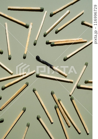 Scattered matches with one burnt matchstick on light green background. 116996729