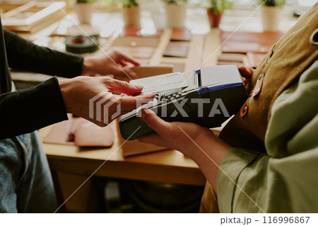 Male hands tapping credit card to buy leather goods while female hands holding payment terminal 116996867
