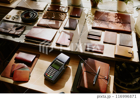 Payment terminal among leather notebooks, card holders and wallets on wooden table 116996871