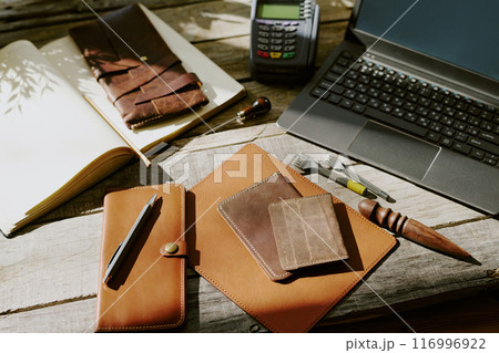 High angle shot of old wooden table with leather goods, leather punches and gadgets 116996922