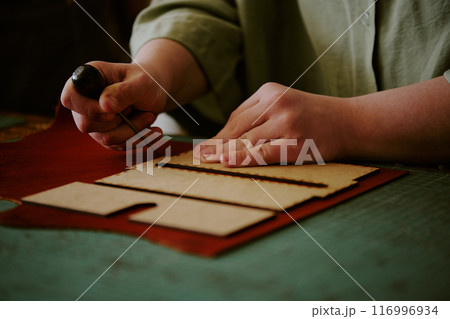 Medium close up of unrecognizable female hands poking leather piece with use of awl Medium close up of unrecognizable female hands poking leather piece with use of awl 116996934